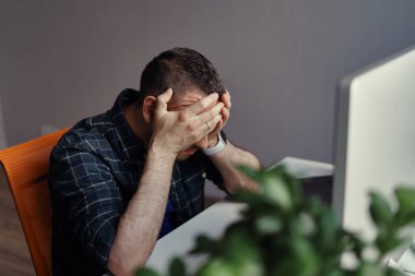 Endişeli adam iki eliyle yüzüne dokunuyor.