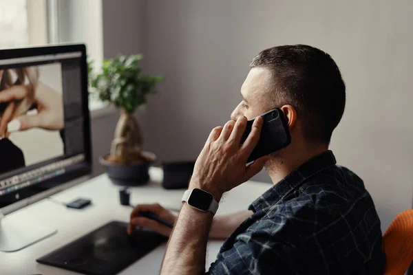 Homem moderno fala por telefone enquanto trabalha no computador — Fotografia de Stock