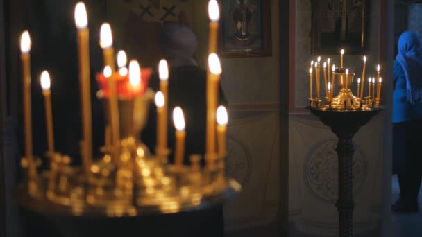 Brennende Kerzen in einer orthodoxen Kirche. Ikonen und Gebet. — Stockvideo