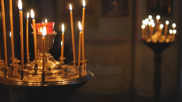Αναμμένα κεριά σε μια Ορθόδοξη Εκκλησία. Εικονίδια και προσευχή. — Αρχείο Βίντεο