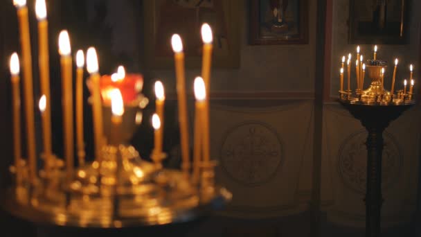 Brinnande ljus i en ortodox kyrka. Ikoner och bön. — Stockvideo