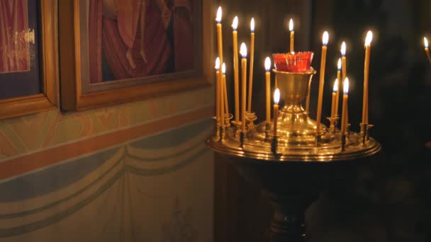 Brandende kaarsen in een orthodoxe kerk. Pictogrammen en gebed. — Stockvideo