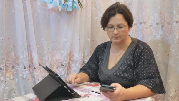Háztartásbeli nő tesz online banki az otthoni élet okostelefon és a tablet hitelkártyával. — Stock videók