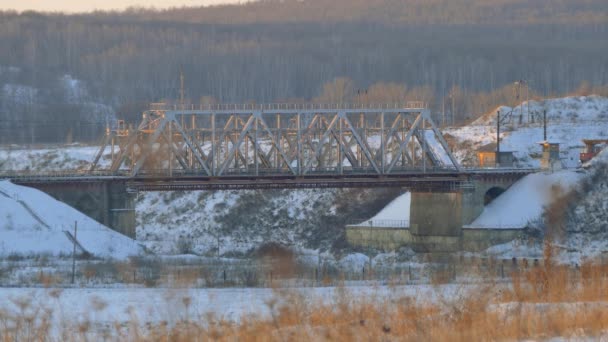 Locomotora de trabajo pasa a través de un puente ferroviario. Paisaje invierno — Vídeos de Stock