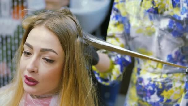 Barbier, teinture pour cheveux, blonde assise dans le salon de beauté. Coiffeur teindre les cheveux . — Video