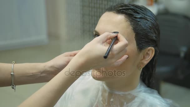 Mujer joven con el pelo en la pintura, para el maquillaje de cejas sentado desde el maestro fabricante de imágenes salón de belleza ultra HD — Vídeo de stock