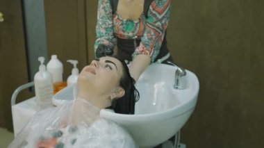 Berber Dükkanı. kafa, yan görünüm. istemciler kaşları bir boya ile uzun siyah saçları güzel kızla boya kadın yıkar.