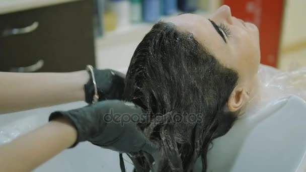 Barbería. cabeza, vista lateral. mujer lava la pintura con el pelo largo negro Chica bonita con una pintura en las cejas de los clientes . — Vídeo de stock