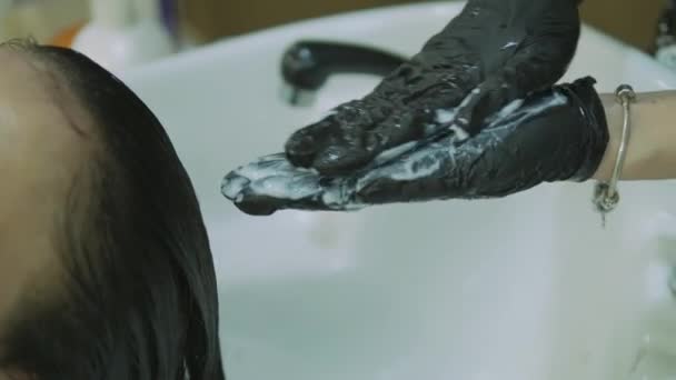 Barbearia. cabeça, vista lateral. mulher lava a tinta com cabelo preto longo Menina bonita com uma pintura nas sobrancelhas clientes . — Vídeo de Stock