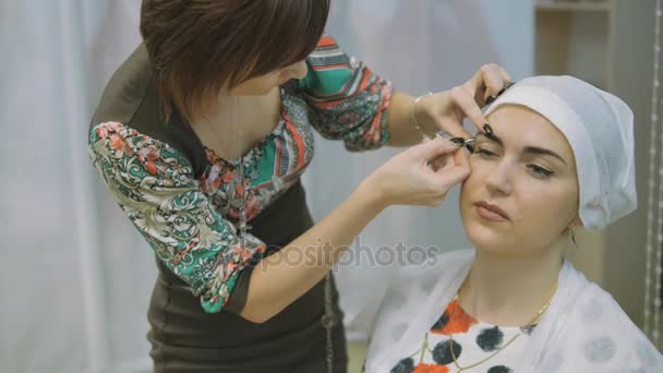 Primer plano de las manos esteticistas usando pinzas en las cejas de las mujeres en el salón de belleza — Vídeos de Stock