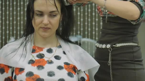Жінка з довгим темним волоссям в салоні краси, укладання волосся з майстром — стокове відео