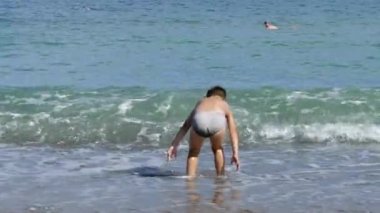 İki genç çocuk, birlikte kumlu bir kıyıda oturan bir dalga olarak banyo.