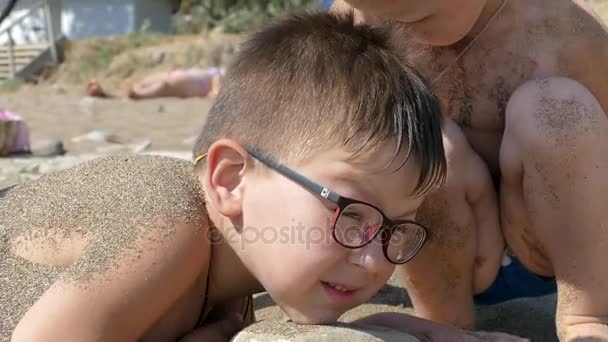 Kleiner Junge am Strand im Sand verscharrt — Stockvideo