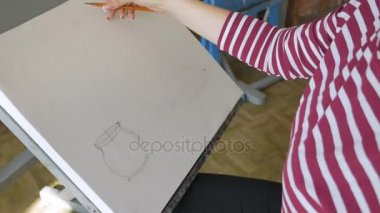 Genç bir sanatçı bir sanat atölyesi olarak kalem doğada bir natürmort bir eskiz çizer.