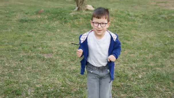 Мальчик бежит к камере и строит счастливые лица. — стоковое видео