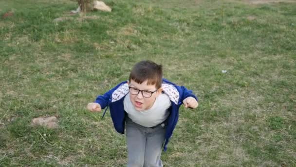 Le petit garçon court à la caméra et construit des visages heureux 