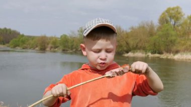 Çocuk sosis willow dal zevk ile sinirli dişleriyle yiyor.