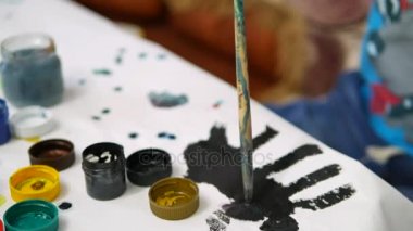 Çocuk evde masada boyalar çizer.