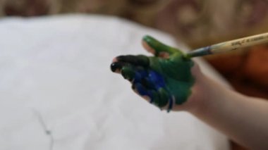 Çocuk evde masada boyalar çizer.