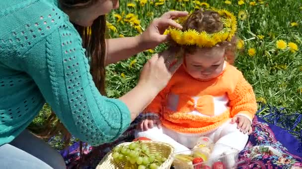 Bambino felice in una radura di primavera in denti di leone con la sua famiglia . — Video Stock