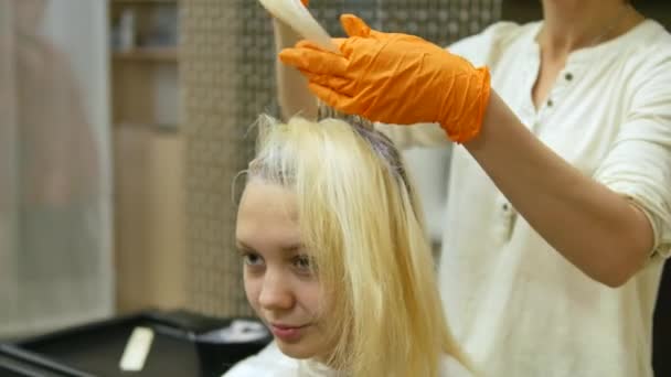 O cabeleireiro faz coloração de cabelo, loira, tinge as raízes do cabelo . — Vídeo de Stock