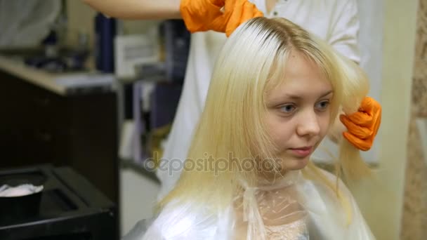 El estilista hace coloración del cabello, rubio, tiñe las raíces del cabello . — Vídeo de stock