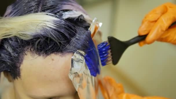 Κομμωτής κάνει χρώμα μαλλιών, Ξανθιά, βαφές μαλλιών σε μπλε χρώμα. — Αρχείο Βίντεο