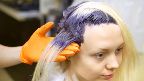 Kapper maakt haarkleur, blonde, haren in blauwe kleurstoffen. — Stockvideo