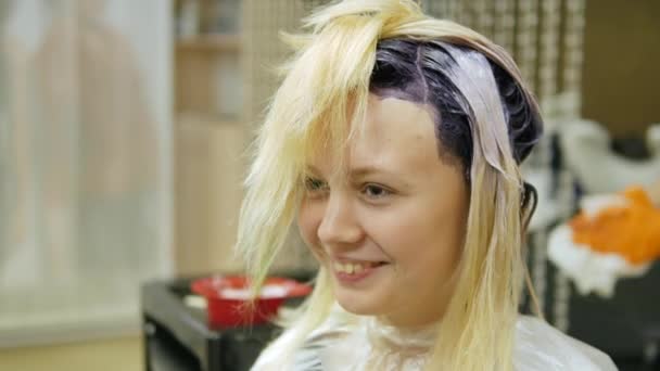 Kapper maakt haarkleur, blonde, haren in blauwe kleurstoffen. — Stockvideo