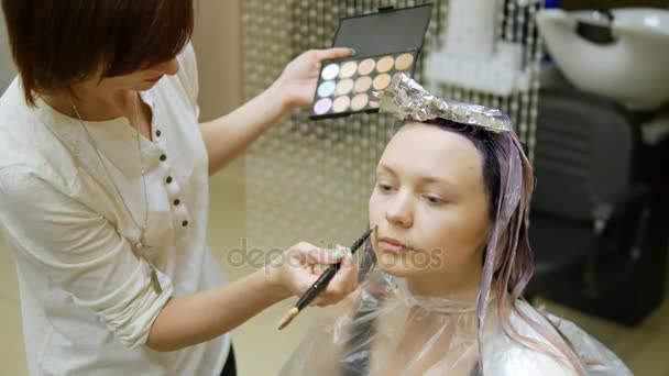 Hair stylist imporre make-up, bionda con i capelli in vernice blu . — Video Stock