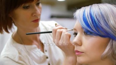 Modeli için makyaj uzmanı. Hafif makyaj genç kız için. Modelleri gösteriliyor. Sahne arkasında moda endüstrisinin.