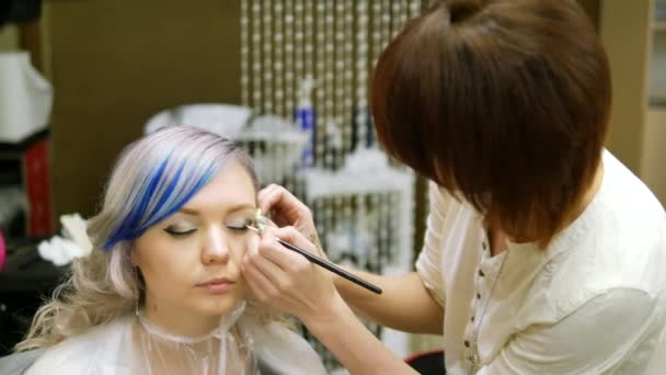 Professionelles Make-up Person ein junges Mädchen mit blauen Haaren. — Stockvideo