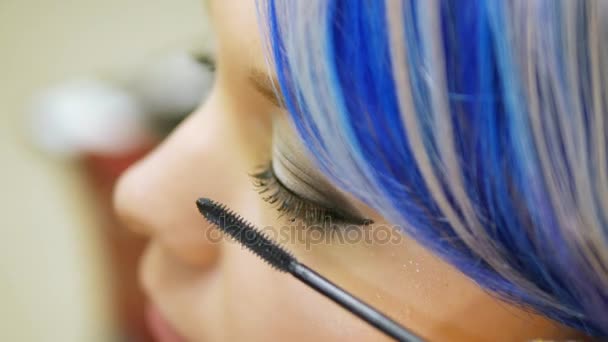 Professionele make-up persoon een jong meisje met blauwe haren. — Stockvideo