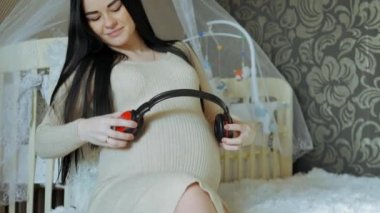 Bebek için bekleyen kadın. Bir kadın müziği dinliyor ve karnı doğmamış bir çocuk ile kulaklık koyar.