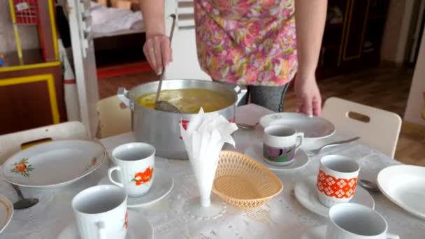 Potten soppa och händer med en tom tallrik och en slev. Stål kastrull från buljong, bestick och köksredskap. Distribution av livsmedel i en kommunal institution. — Stockvideo