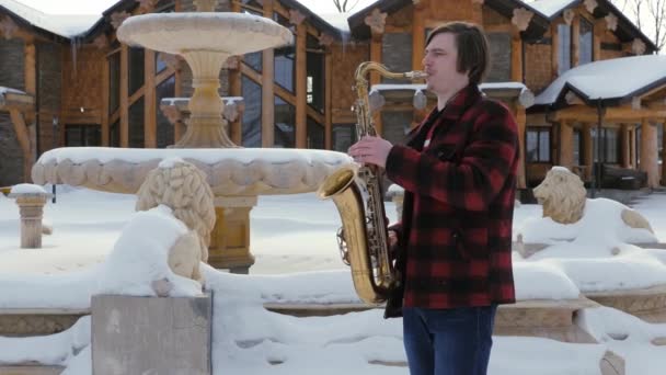 Саксофоніст грає на саксофоні, взимку — стокове відео