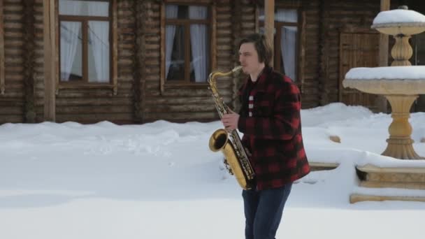 Саксофонист играет на саксофоне зимой — стоковое видео