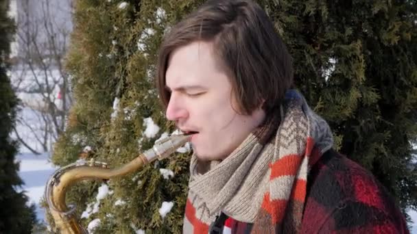 Hudebník hraje na saxofon, v zimě — Stock video