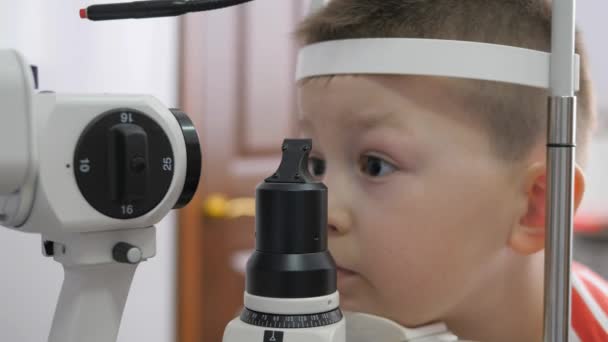 Niño en una clínica oftálmica. Niño mirando un tonómetro en el examen de los ojos — Vídeos de Stock