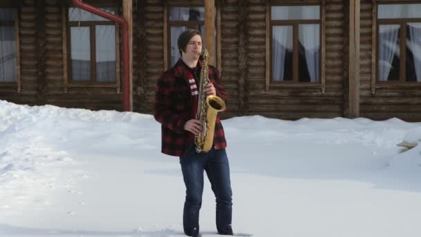 Saxofonista toca el saxofón, en invierno — Vídeo de stock