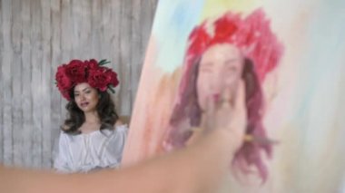 Sanatçı doğadan bir portre çizer. Sanatçı doğadan bir portre çizer. Kayan kamera odaklama, kamera çekimde. Scarlet peonies oturan poz kafasında bir çelenk ile güzel model