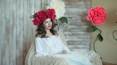Sanatçı doğadan bir portre çizer. Sanatçı doğadan bir portre çizer. Kayan kamera odaklama, kamera çekimde. Scarlet peonies oturan poz kafasında bir çelenk ile güzel model