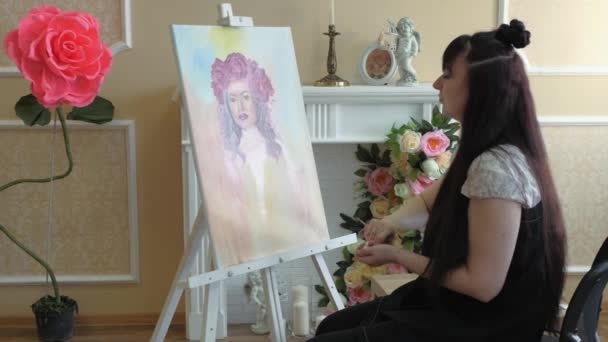 Artist draws a portrait from nature. The artist draws a portrait from nature. Floating camera focus, camera in motion. Beautiful model, with a wreath of scarlet peonies on his head, posing sitting in — Stock Video