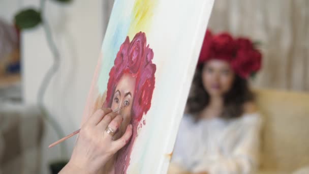 Kunstenaar trekt een portret uit de natuur. De kunstenaar trekt een portret uit de natuur. Zwevende focus van de camera, camera in beweging. Mooi model, met een krans van scarlet pioenrozen op zijn hoofd, die zich voordeed in zit — Stockvideo