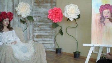 Sanatçı doğadan bir portre çizer. Sanatçı doğadan bir portre çizer. Kayan kamera odaklama, kamera çekimde. Scarlet peonies oturan poz kafasında bir çelenk ile güzel model