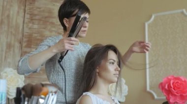 Makyaj sanatçı stilist modeli ile çalışır. Kuaför saç şekillendirme modeli yapar. kadın bir şekillendirici kızlar uzun saçlı çalışıyor.