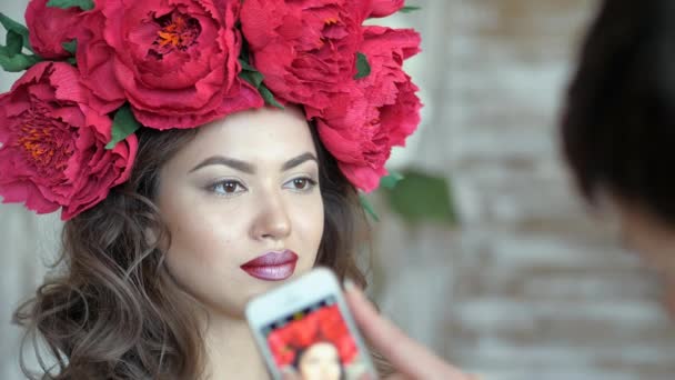 Artista de maquillaje estilista trabaja con modelo. mujer está tomando fotos de una modelo de chica en un teléfono inteligente . — Vídeos de Stock