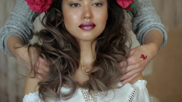 Makeup artist stylist works with model. Womens hands straighten out the long dark curly hair of the model. — Stock Video