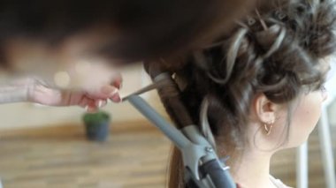 Makyaj sanatçı stilist modeli ile çalışır. Kuaför saç şekillendirme modeli yapar. kadın bir şekillendirici kızlar uzun saçlı çalışıyor. Kuaför bukleleri düz saç üzerinde yapar.