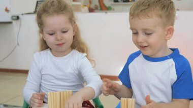 Çocuk Oyun Odası geliştirmek. Sınıflar eğlenceli sırasında duygular genç çocuk. Erkek ve kız masada oturan tahta bloklarla oynama.
